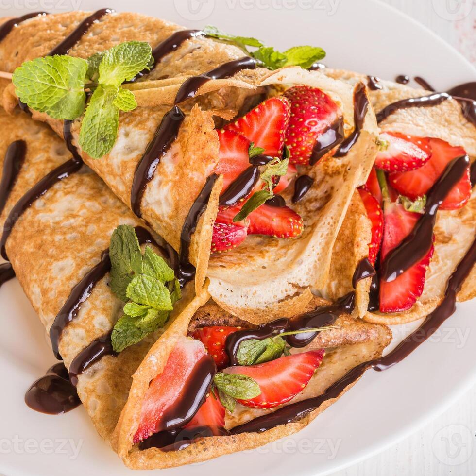 A plate topped with crepes and strawberries photo