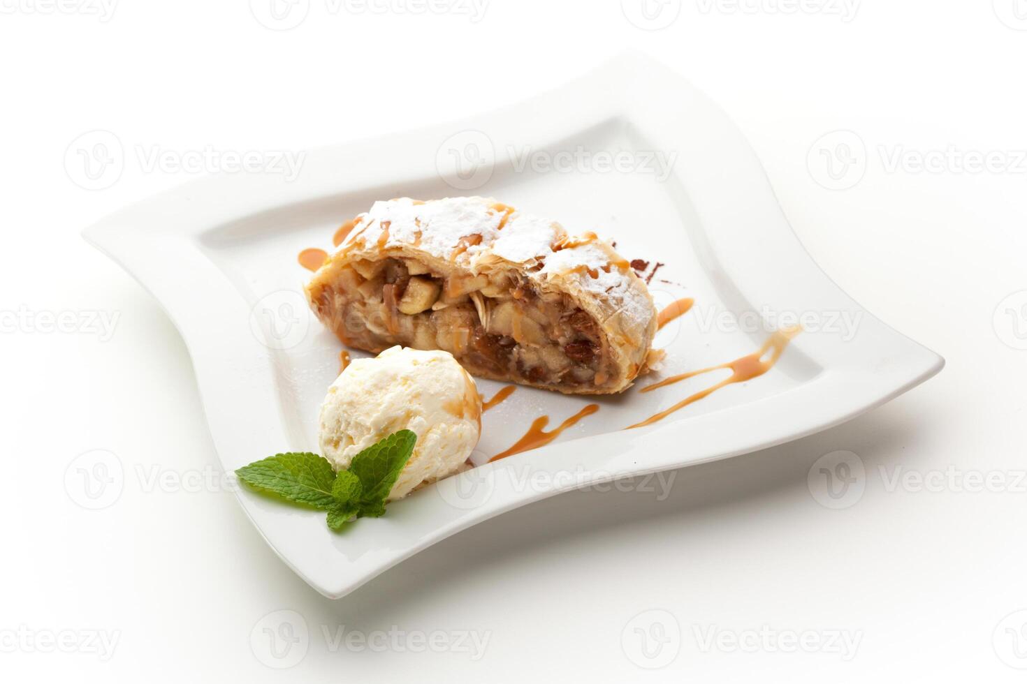 A dessert on a white plate with ice cream and a mint leaf photo