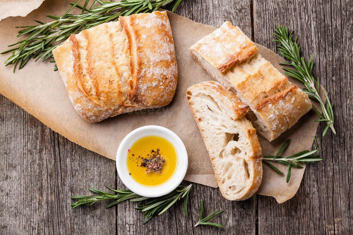 Bread with olive oil and rosemary on a wooden table photo