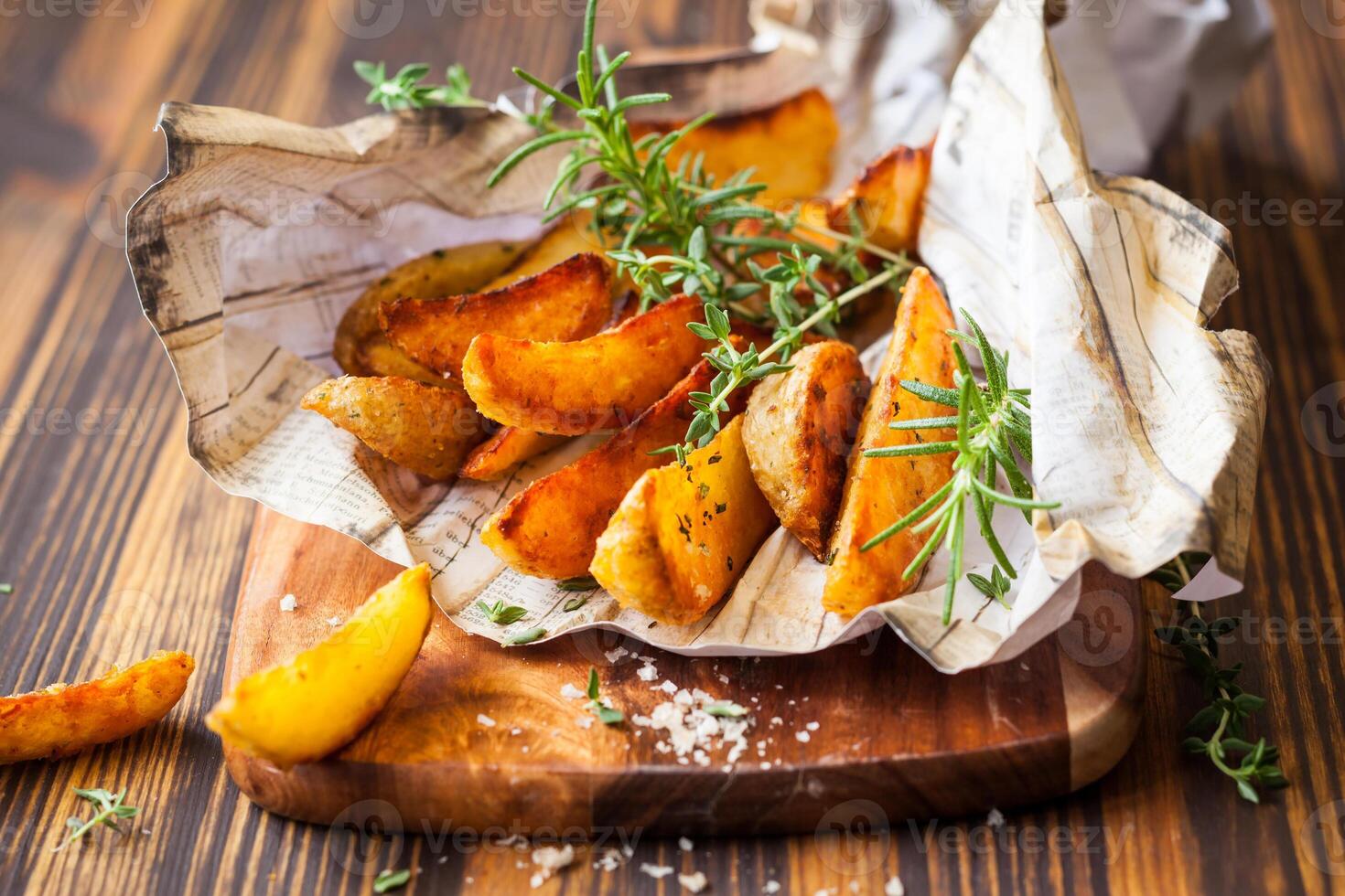 Baked potato wedges with herbs and salt on a wooden cutting board photo