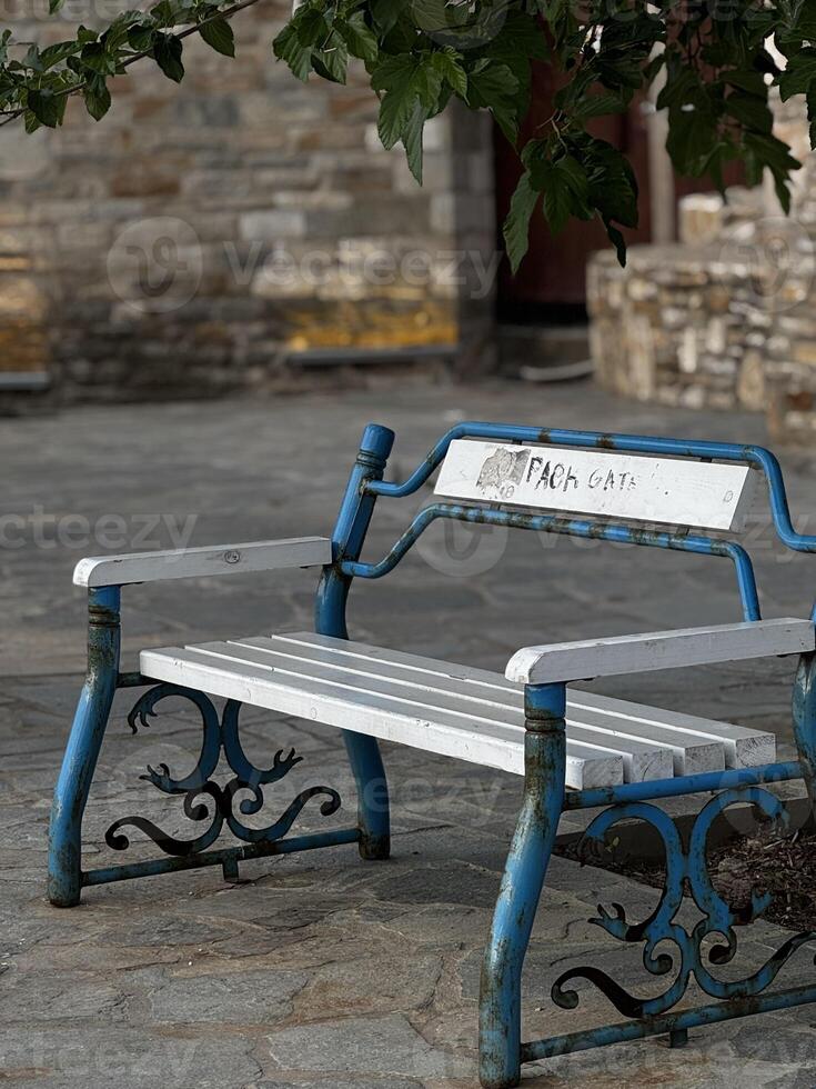 Close-up of classic blue and white benches beside an old stone wall in a sunlit Greek village, perfect for travel scenes. photo