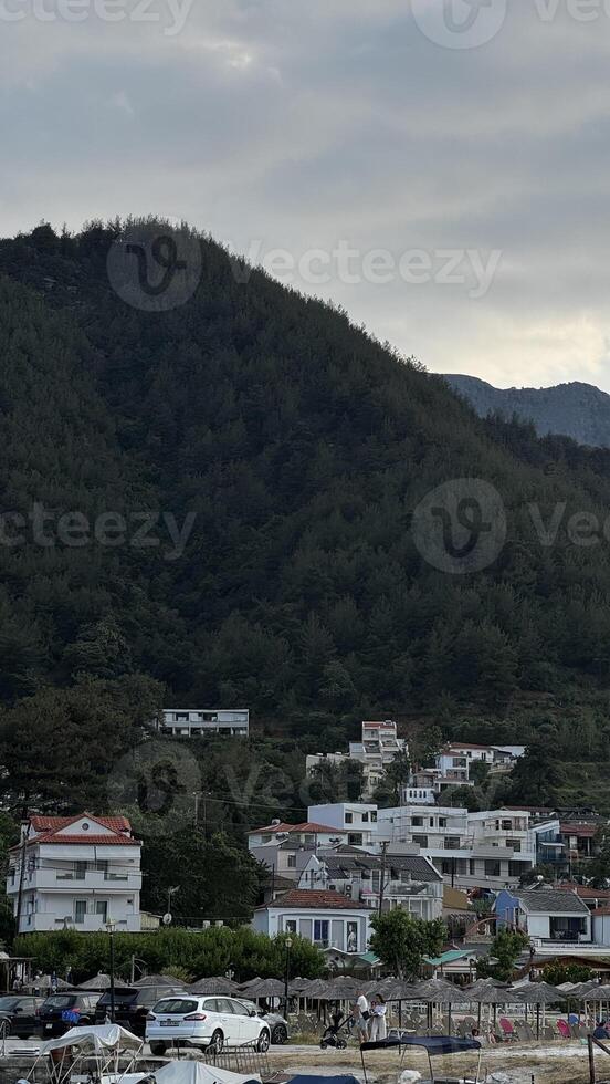 Detailed view of white and red-roofed buildings nestled at the foot of a wooded mountain in Thassos, Greece. photo