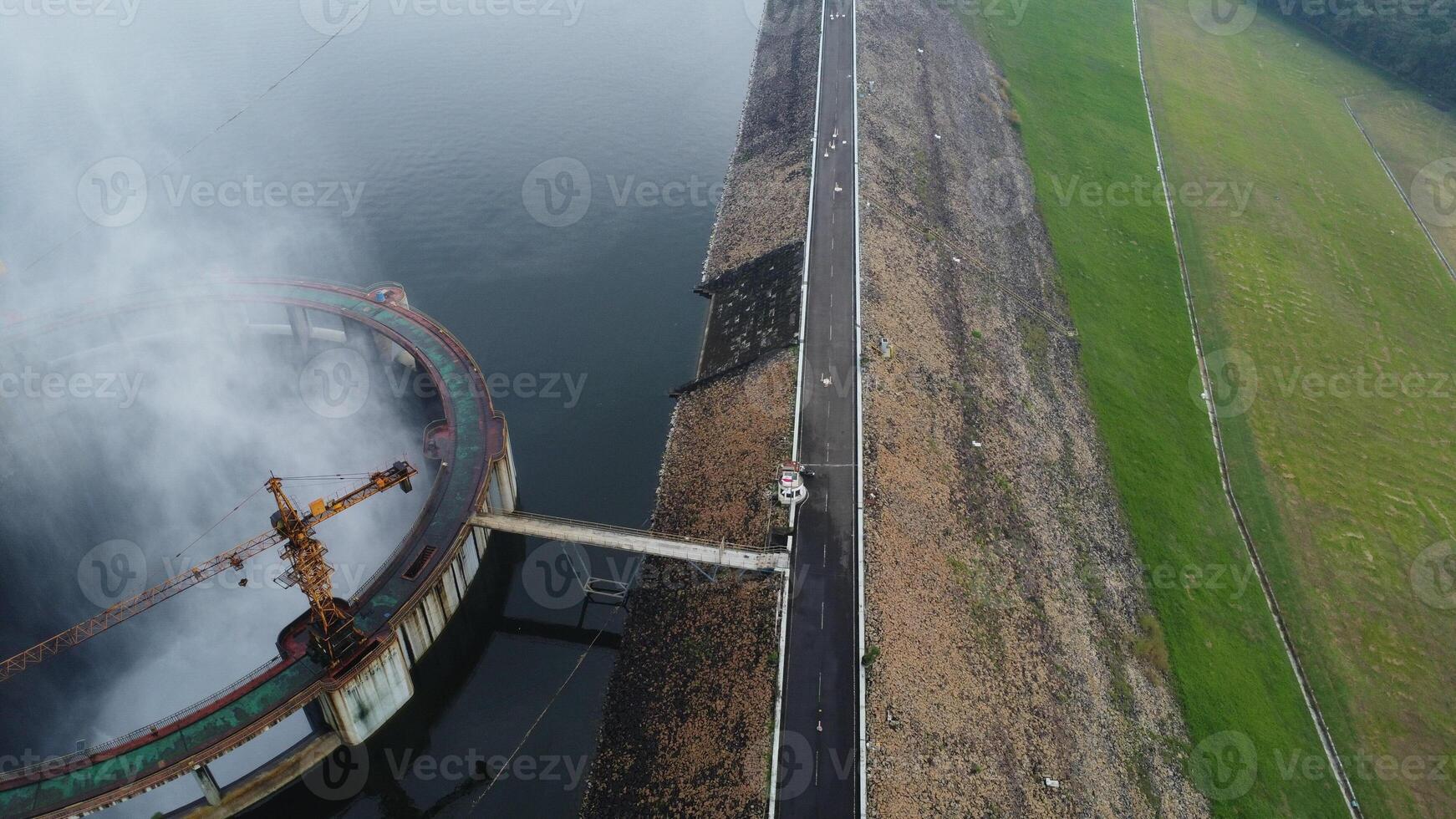 A breathtaking landscape featuring a river dam nestled among mountains under a vast sky, with a serene lake and distant coast photo