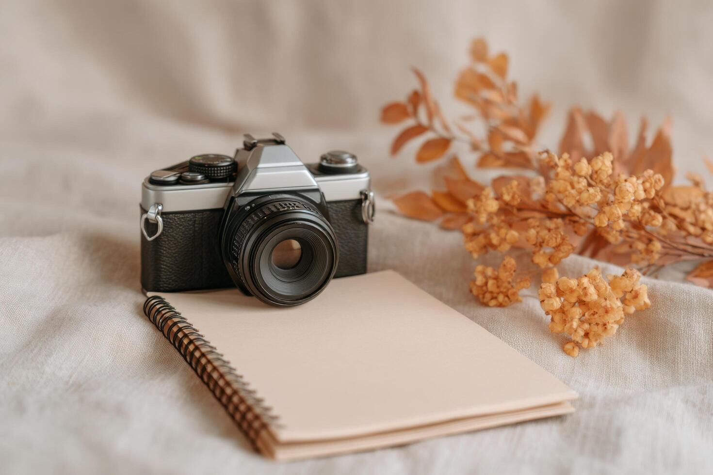 Vintage Camera and Notebook Still Life Photography Autumnal Hues and Dried Flowers. A nostalgic scene capturing the essence of analog photography and autumn's warm tones. photo