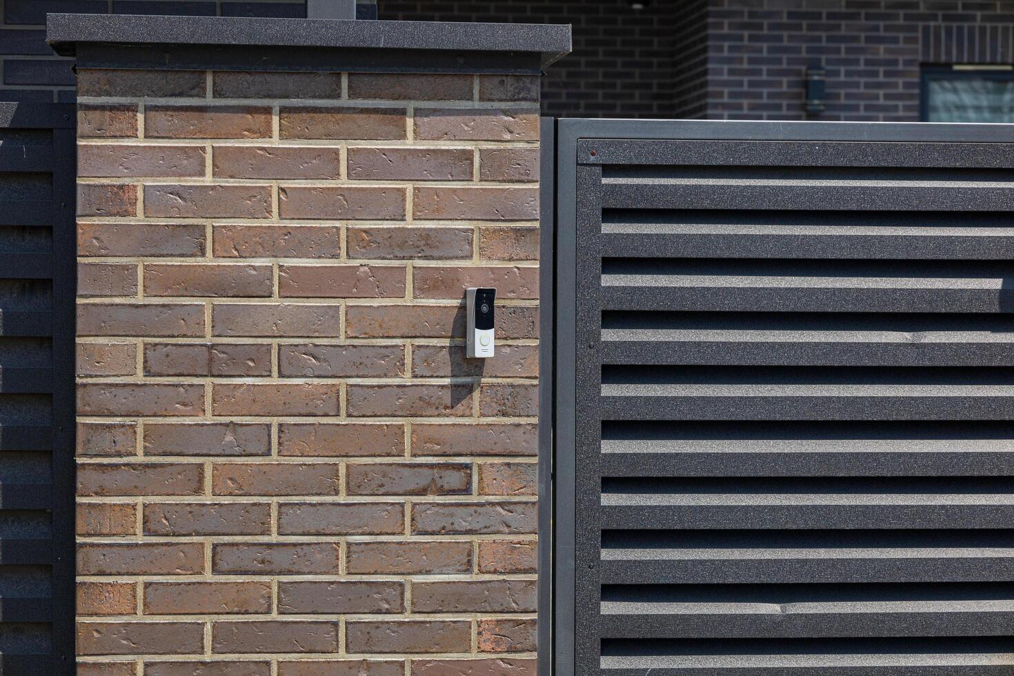 A sleek intercom device is installed on a stylish brick wall, facilitating secure communication at the entrance of a contemporary property photo