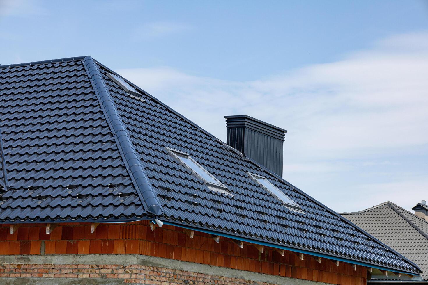 New roof with metallic tiles and skylights enhances the modern design of the home while providing durability and style photo