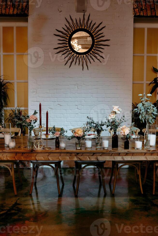 Elegant dining setup with floral centerpieces and sunburst mirror in rustic setting photo