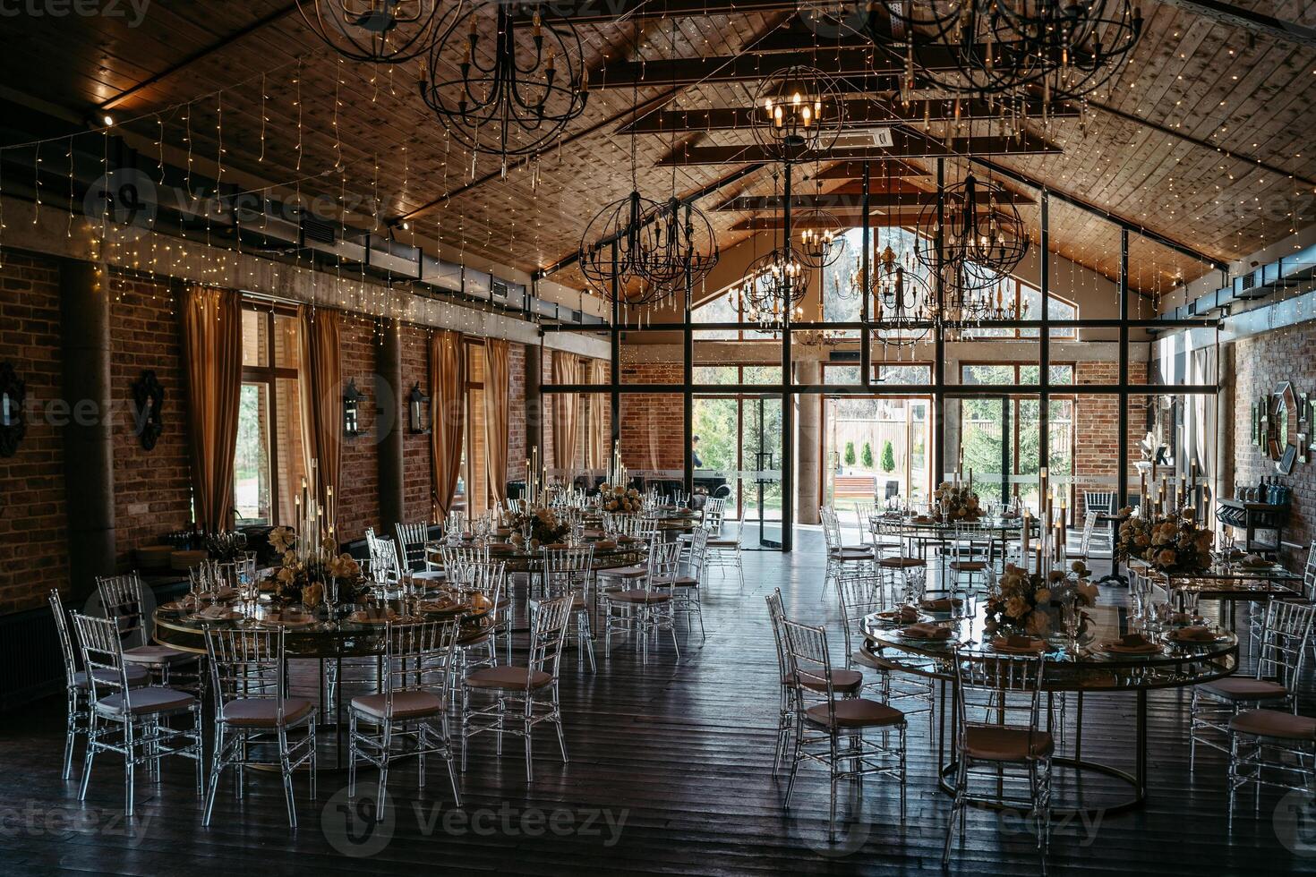 Elegant rustic wedding venue with round tables and chandeliers photo