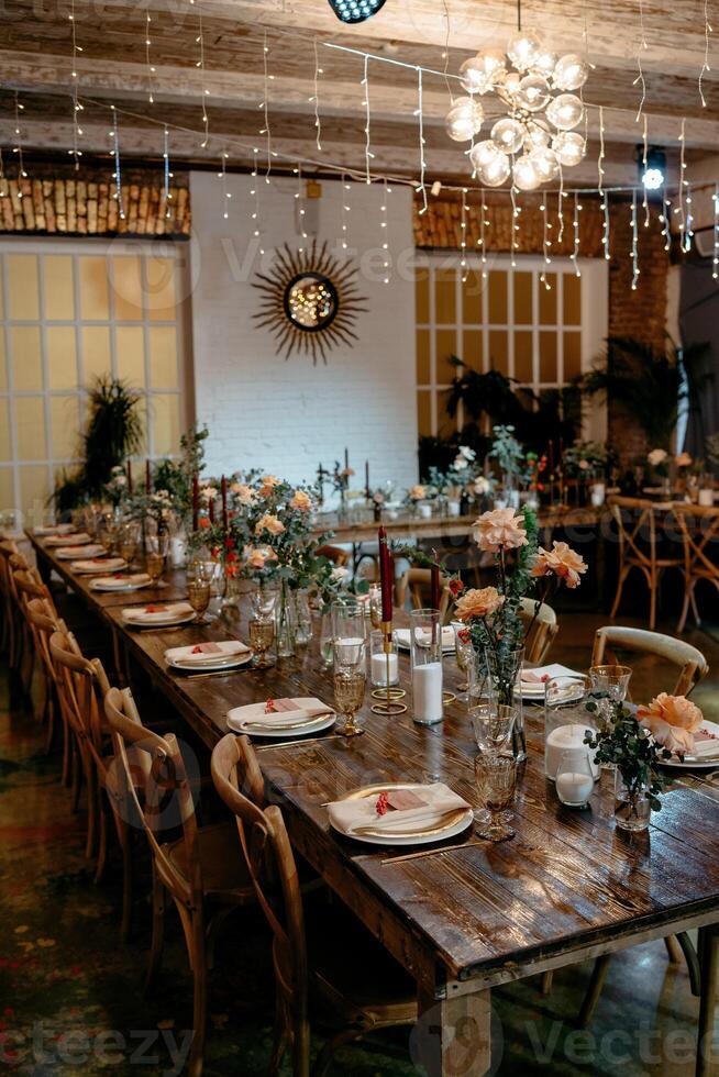 Rustic wedding reception table setting with floral decor and wooden chairs photo