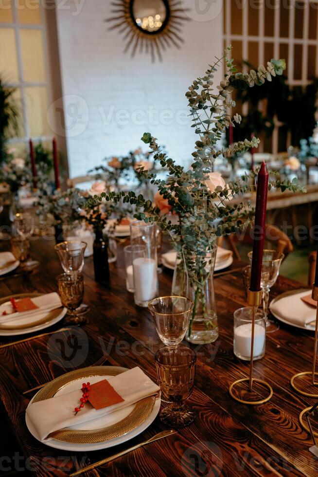 Elegant rustic dinner setting with eucalyptus decor and candles in a cozy ambiance photo