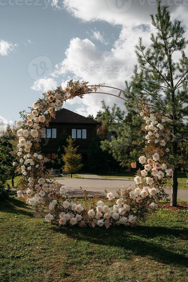 Floral wedding arch with white and pink blossoms in sunlit garden setting photo