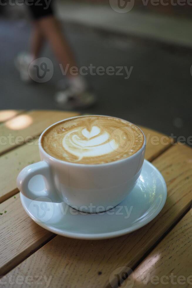 Coffee cup with latte art on wooden table outdoors photo