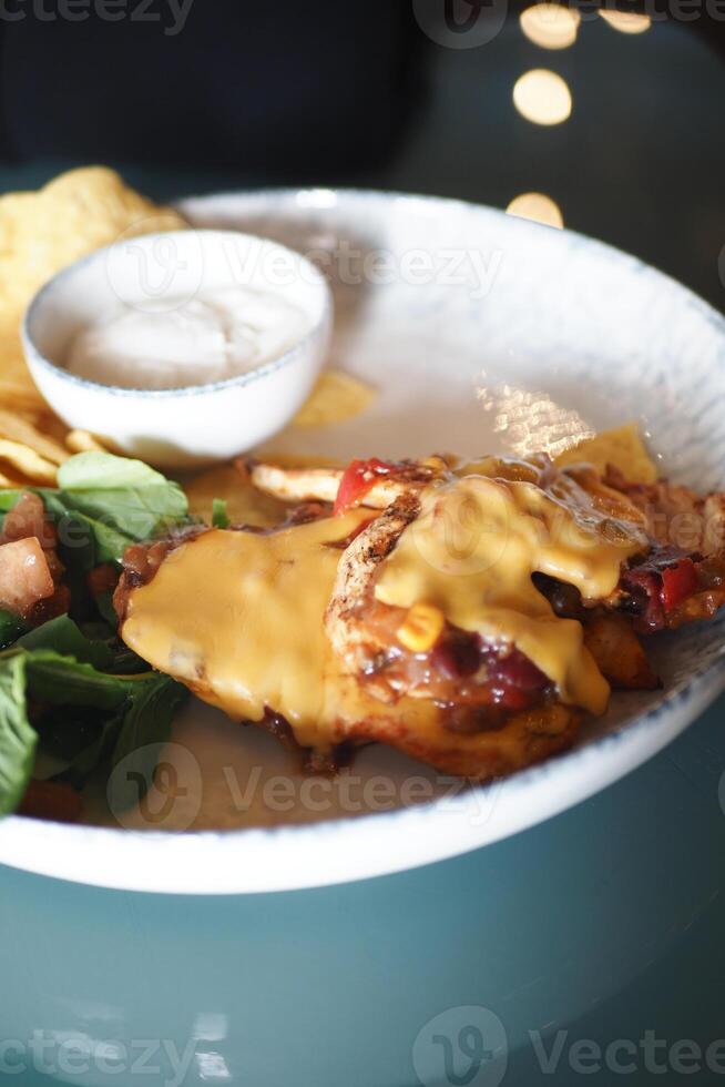 Delicious plate of chicken with cheese sauce and salad photo
