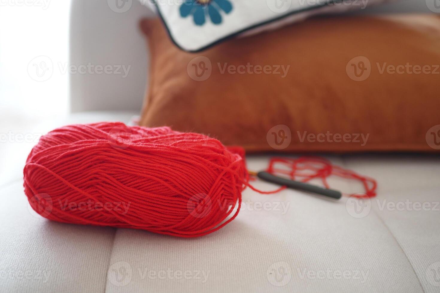 Yarn and crochet hook on a cozy sofa setup photo