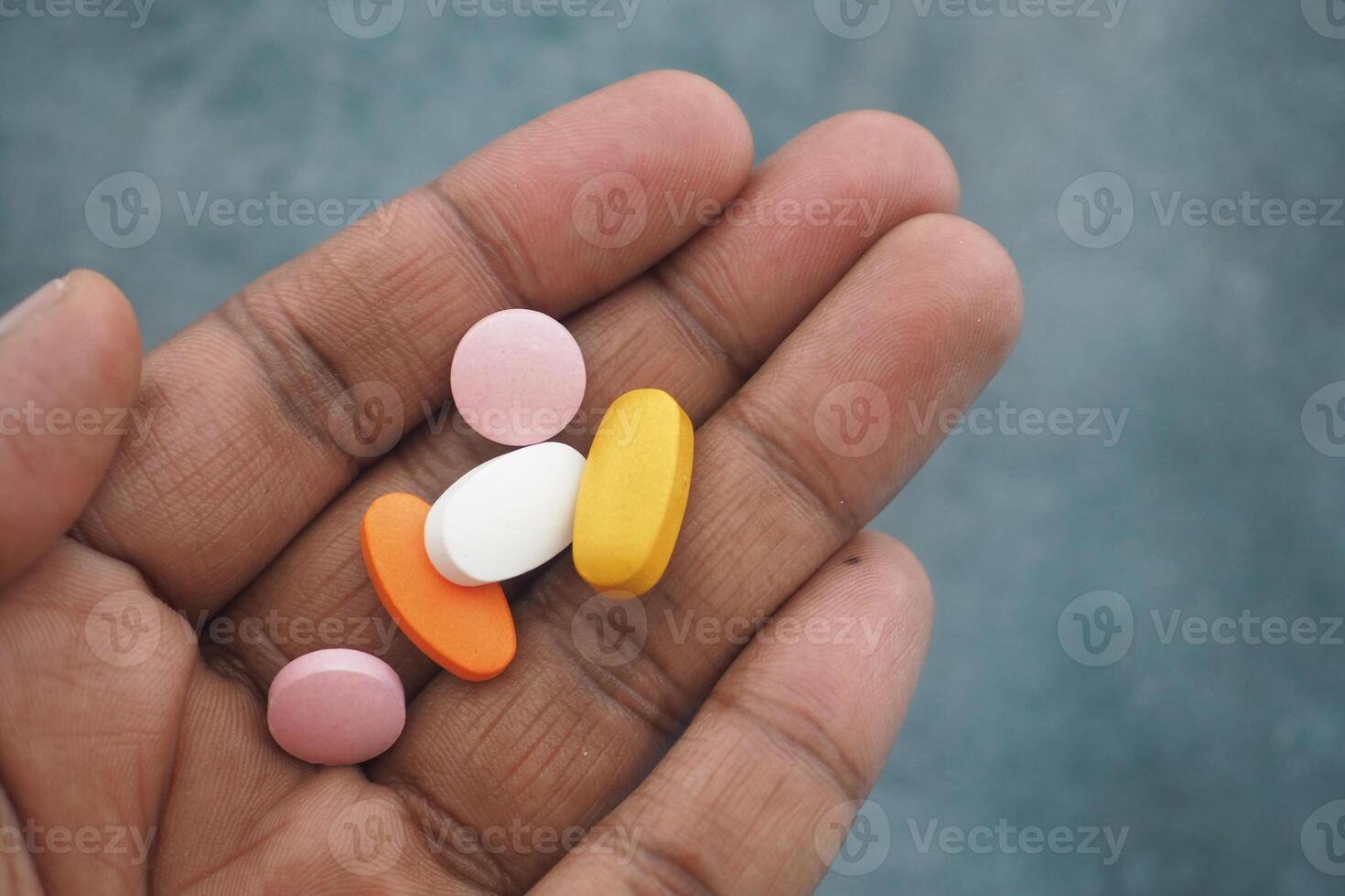Hand holding various colorful pills for health and wellness photo