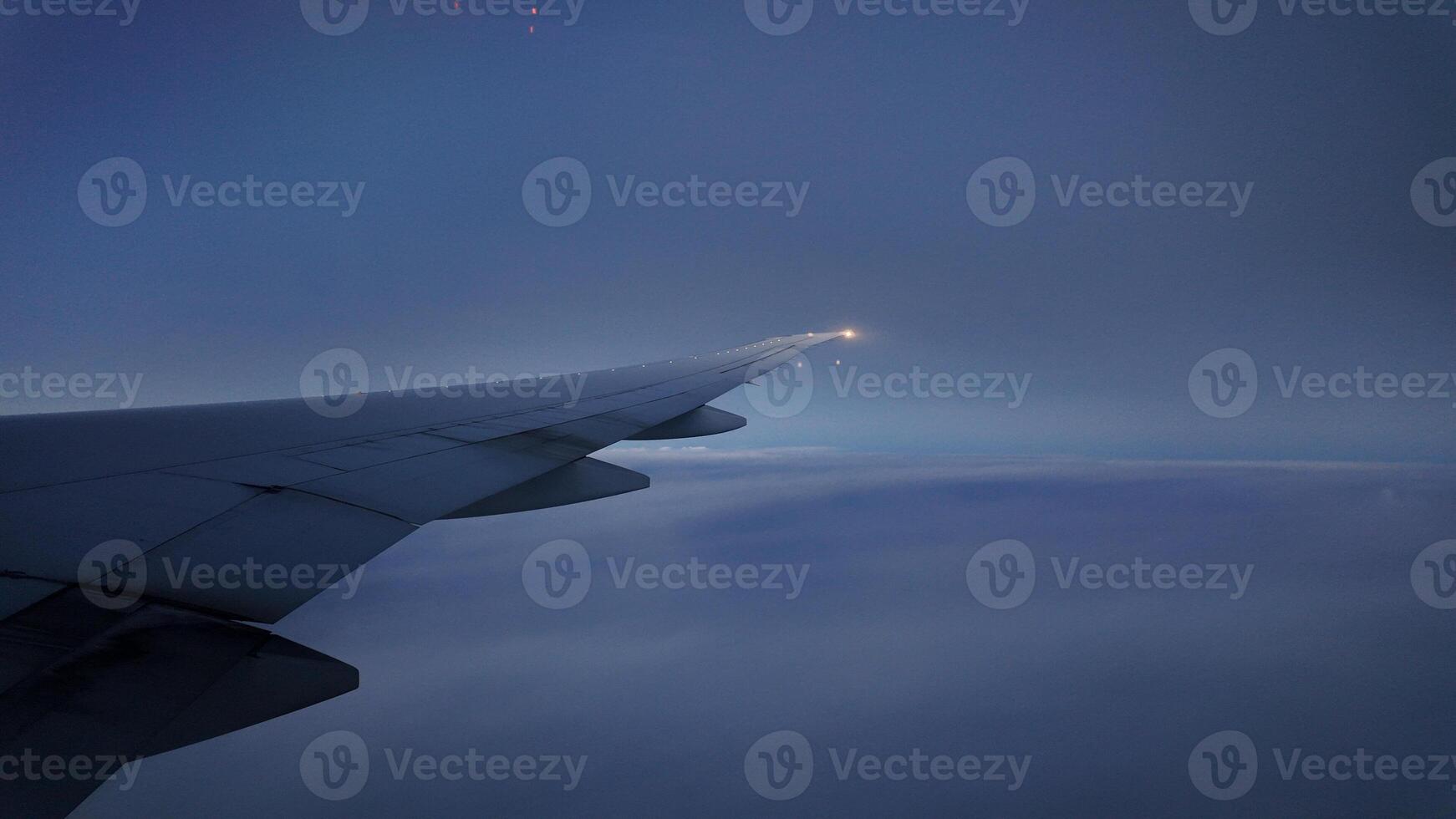 Wing of an aircraft gliding through twilight clouds photo