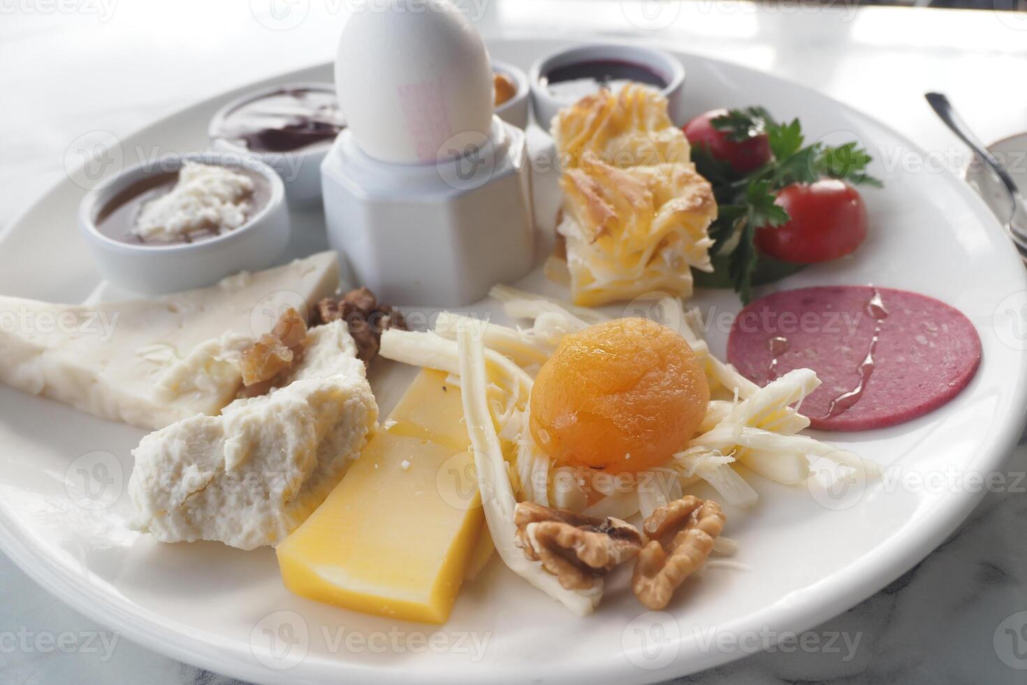 A turkish breakfast platter featuring cheese, eggs, fruits, and spreads. photo