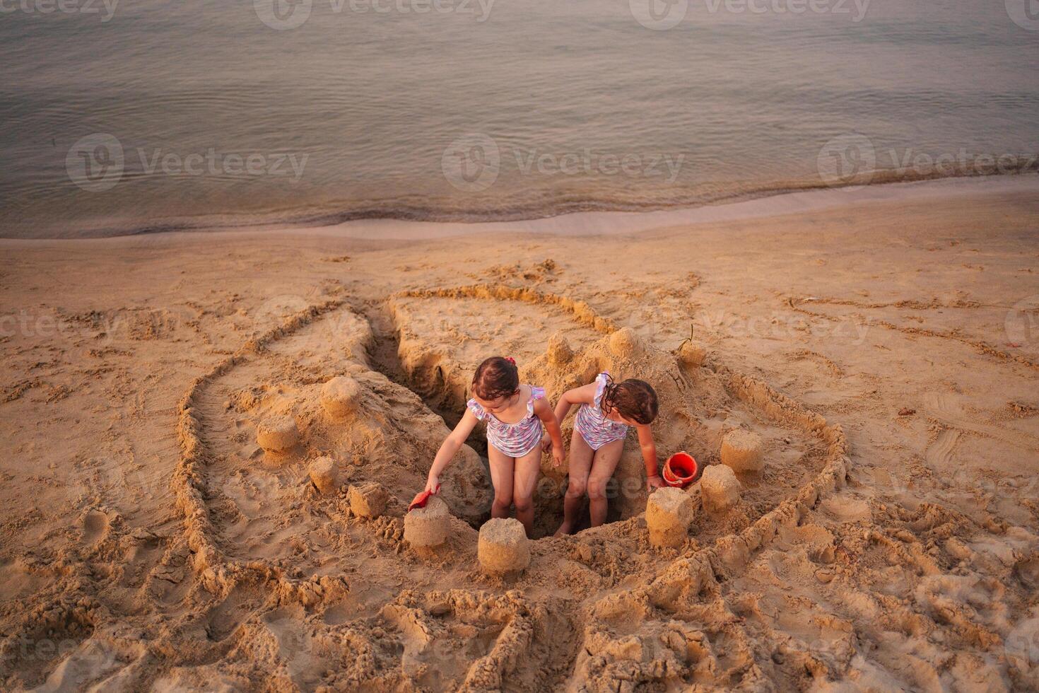 Siblings build an elaborate sandcastle on a sunny beach afternoon photo