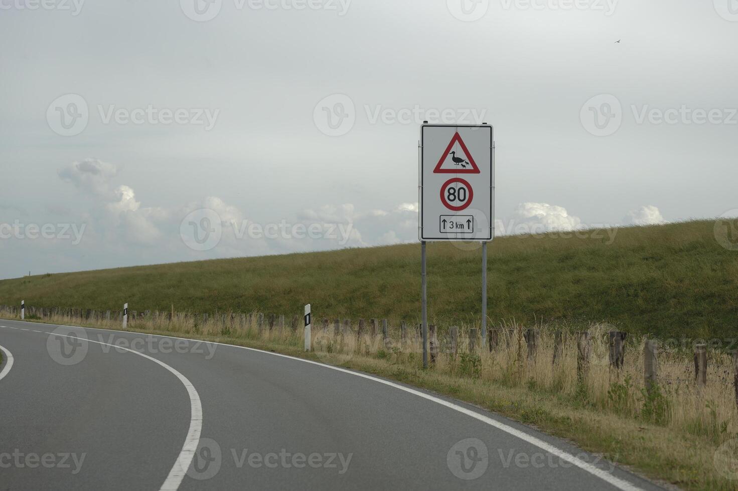 Country road in front of the dike of North Sea coast in Dagebuell is a sign for speed limit 80 kmh photo