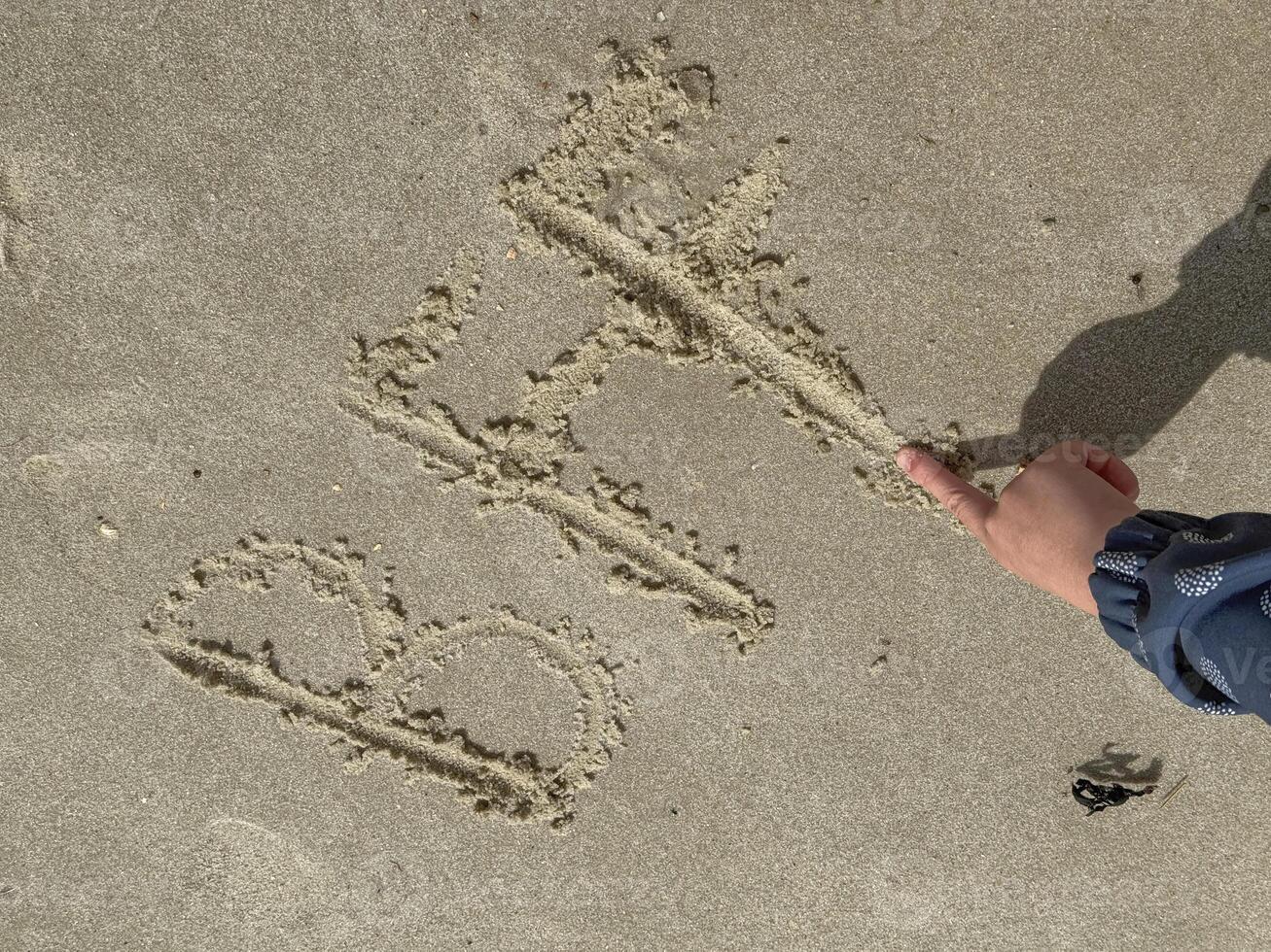 A hand of a child has written BFF Best Friends Forever in the sand on the beach of the North Sea coast photo