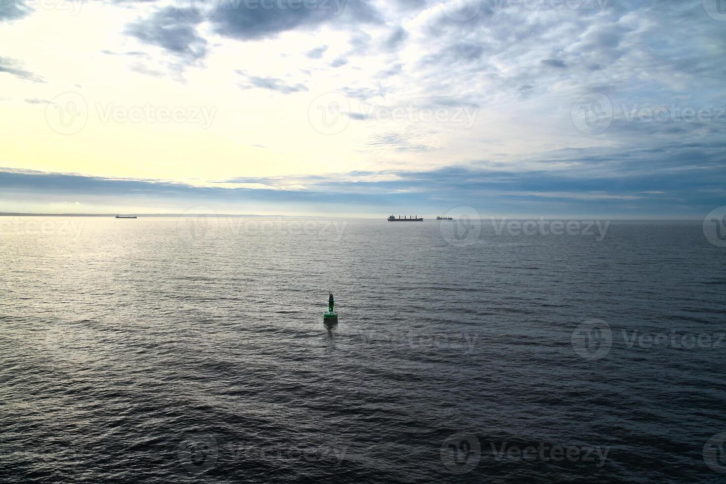 Green buoy in the calm sea at sunrise, ships on the horizon photo