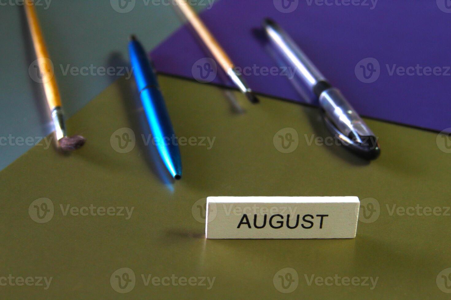 On a dark multi-colored background lie stationery, in the foreground is the word August. photo