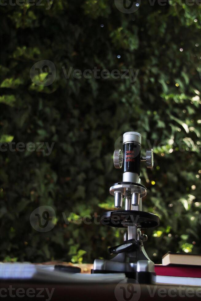 Microscope on a desk with nature background photo