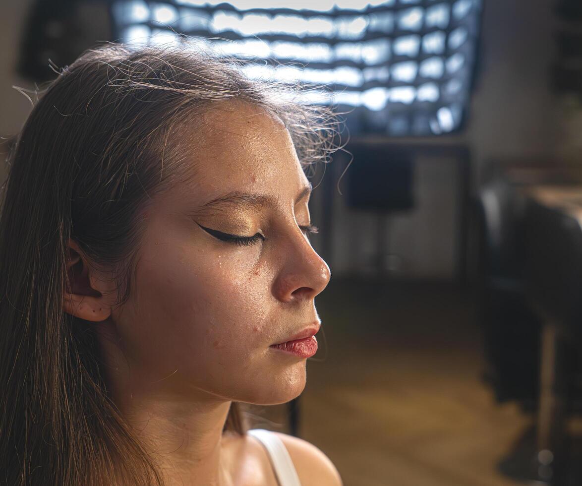 Confident brunette poses in studio light, highlighting her flawless makeup. The golden earrings add a stylish accent photo