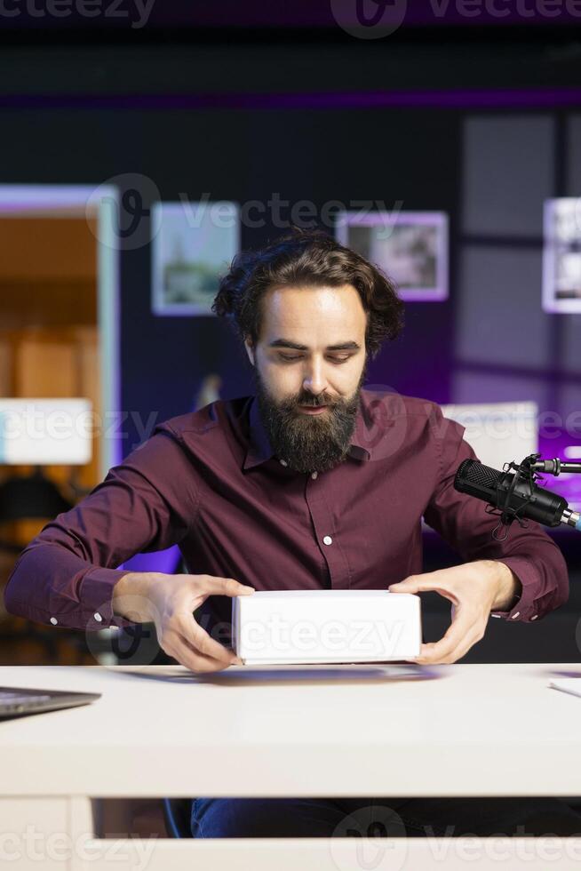 Tech content creator filming packaged product unboxing, giving reasons to purchase it. Influencer recording urging subscribers to buy advertising sponsor merchandise photo