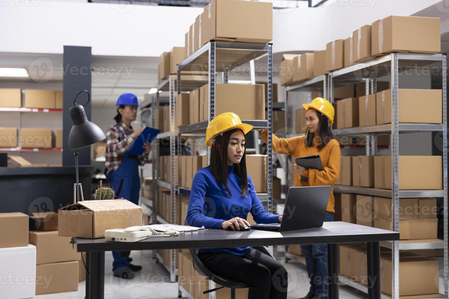 Asian staff member in a local brand supply room prepares products and taped boxes for shipment. Small business activity uses in house logistics for storage and delivery services. photo