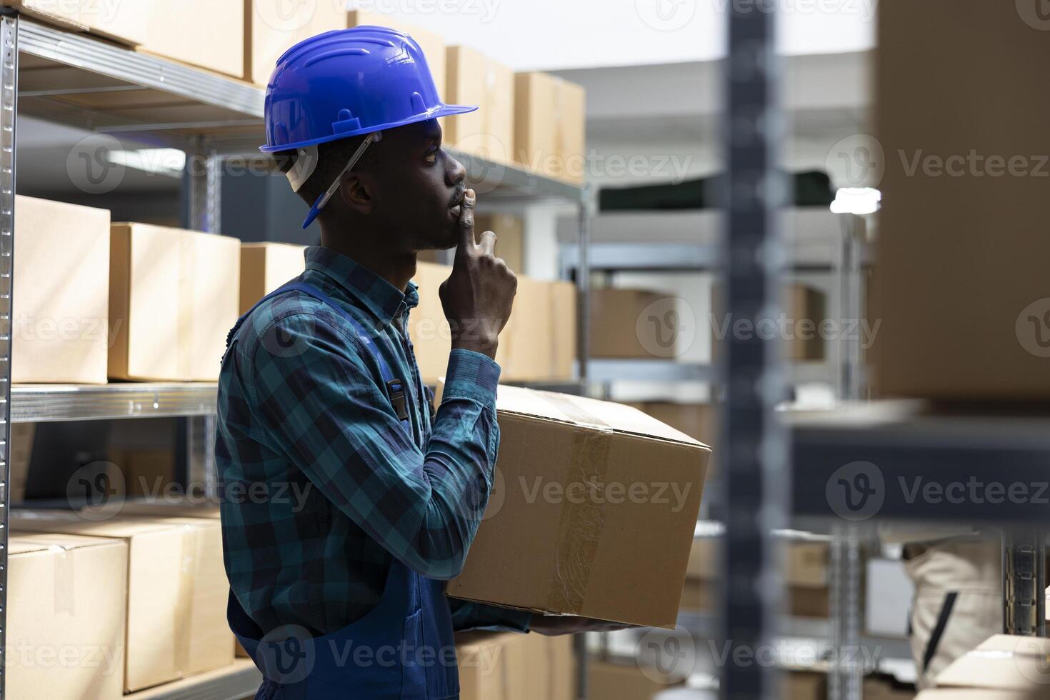 Black worker manages business logistics to ensure operational control of the merchandise inventory system. Shelving units in a warehouse lined with packages and boxes, storage process. photo