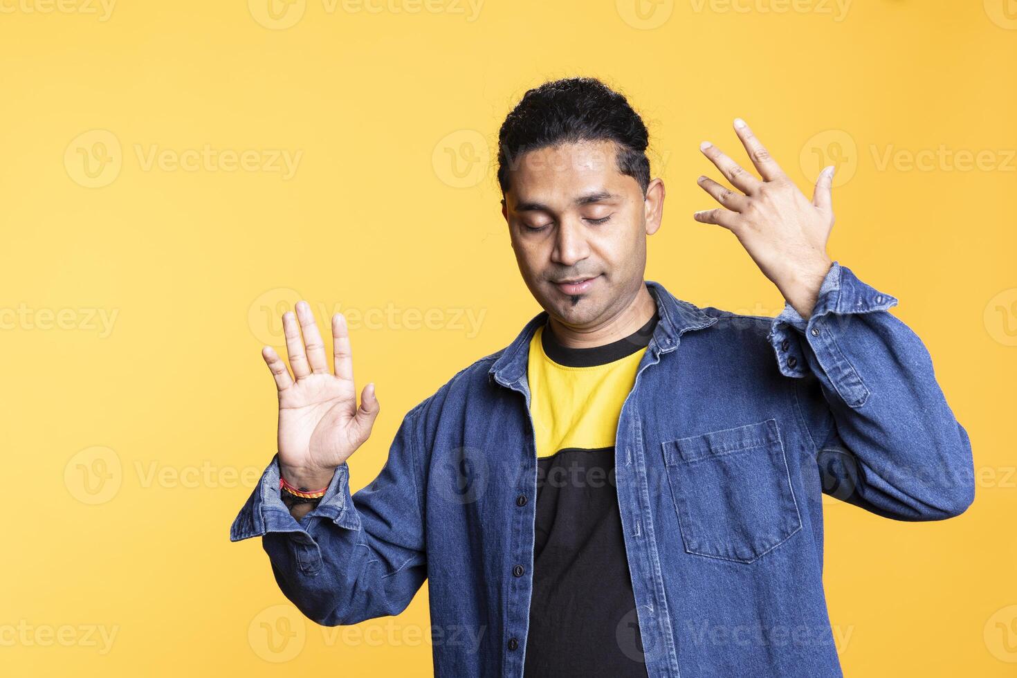 Indian cheerful man waving his hands and greeting people with a smile on his face, feeling pleased and ecstatic with good vibes. Confident friendly guy welcoming someone, upbeat. photo