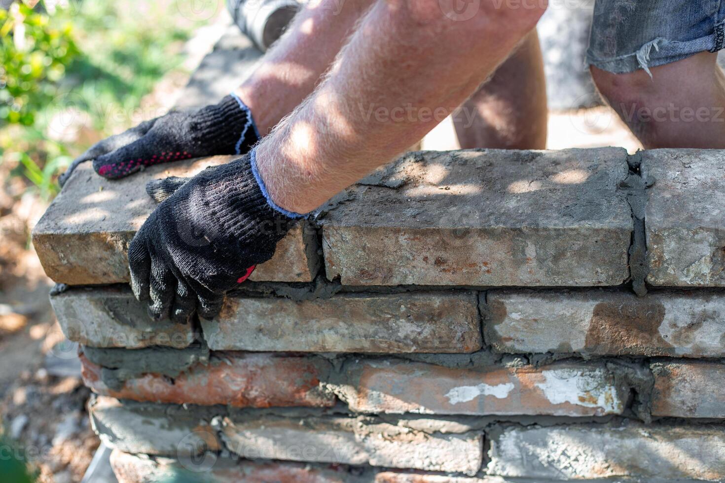 Bricks being laid on a partially built brick structure with mortar. Construction of a barbecue. photo