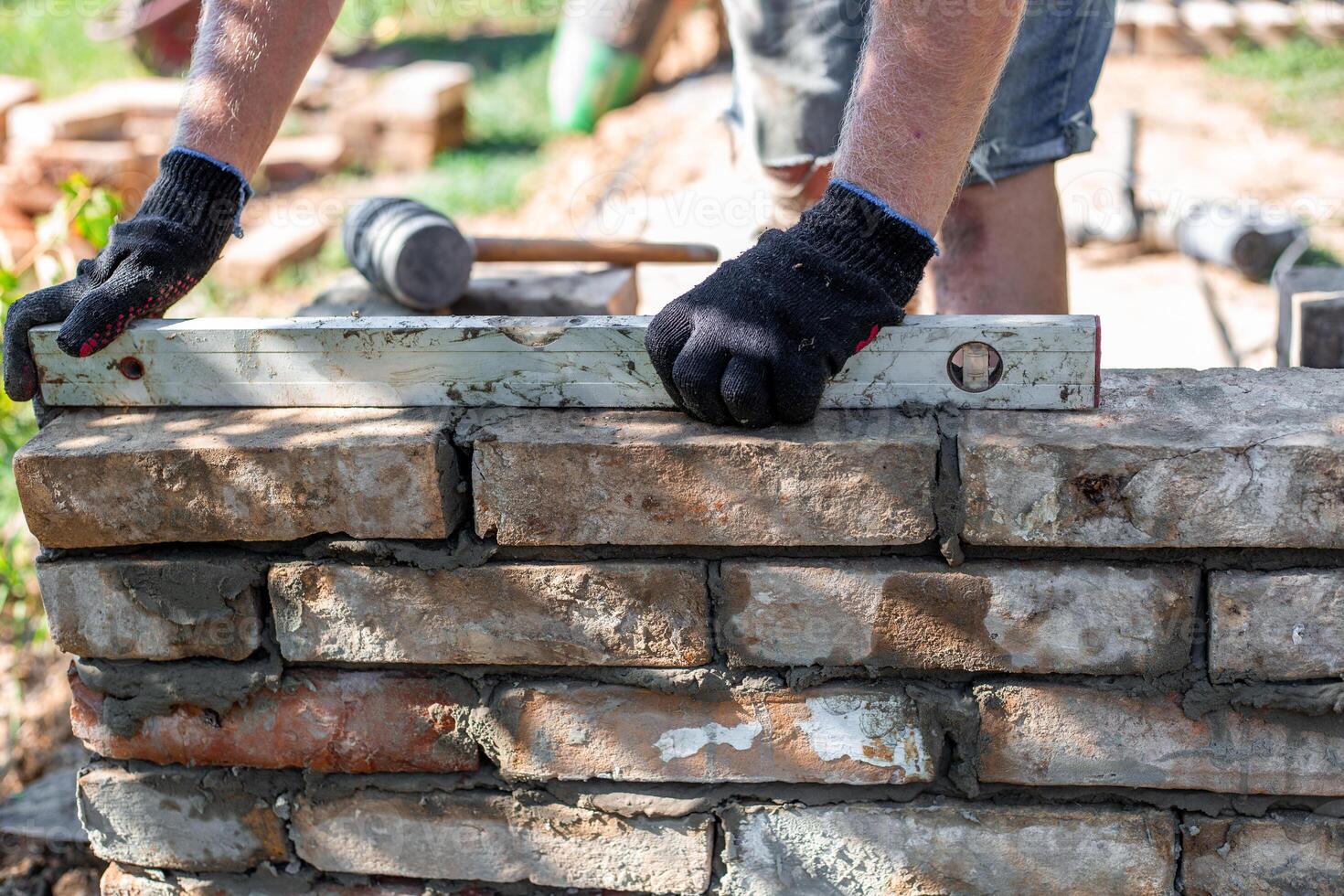 Close-up of leveling bricks during construction of brick structure using spirit level. photo