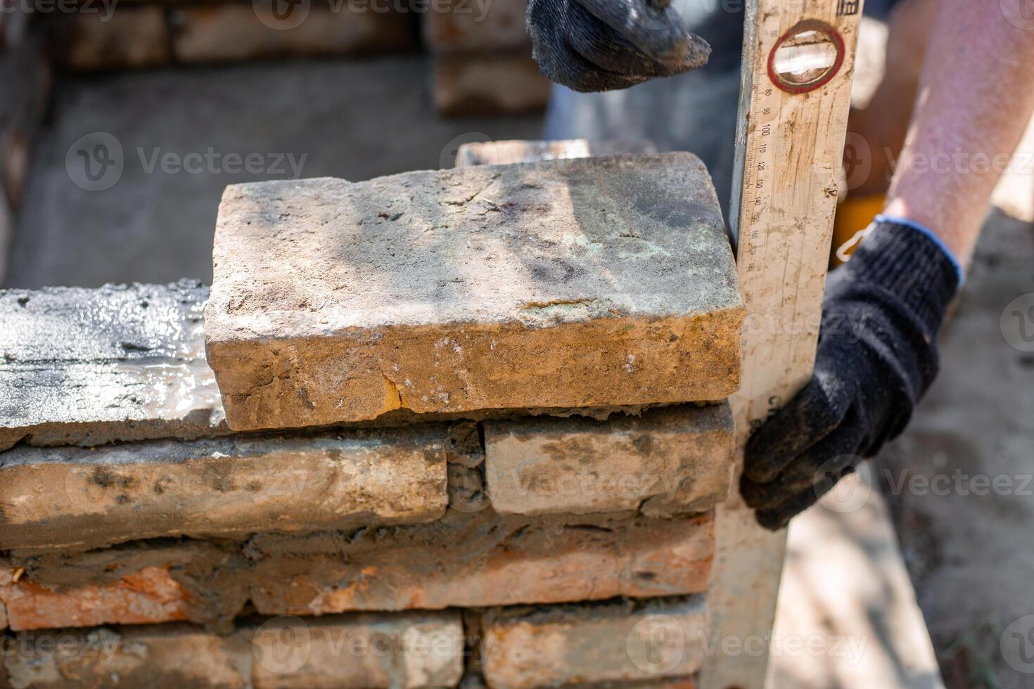 Closeup of leveling bricks during construction of brick structure using spirit level. photo