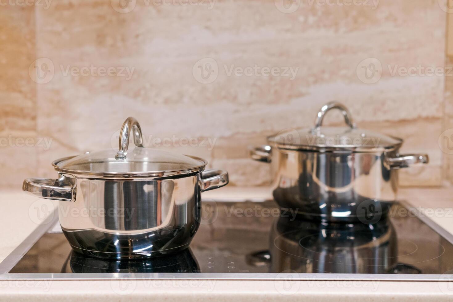 two chrome pans with stota lids on an electric touch plate. close-up. home cooking concept photo