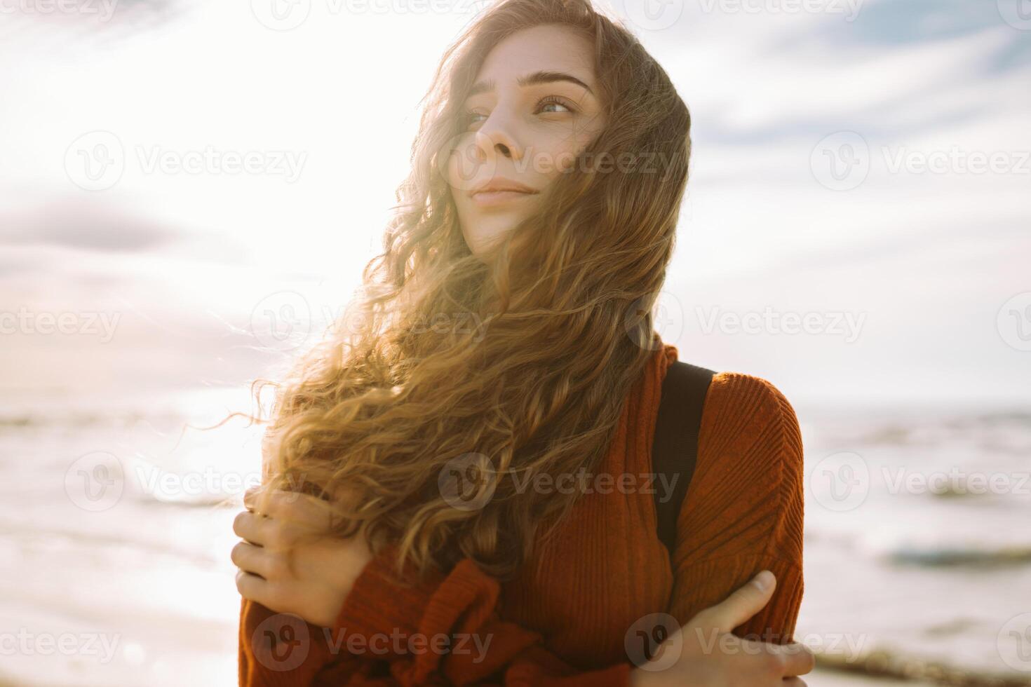Woman enjoying breezy. near vibrant red lighthouse at sunset. Travel, weekend, lifestyle concept. photo