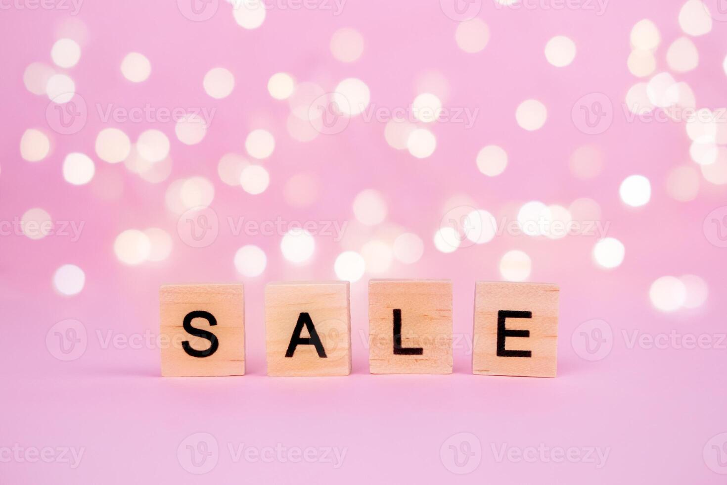 Words Sale on a blurred pink background with beautiful bokeh garland lights. With copyspace Concept of holidays christmas, valentine's day, black friday, mothers day and seasonal discounts photo
