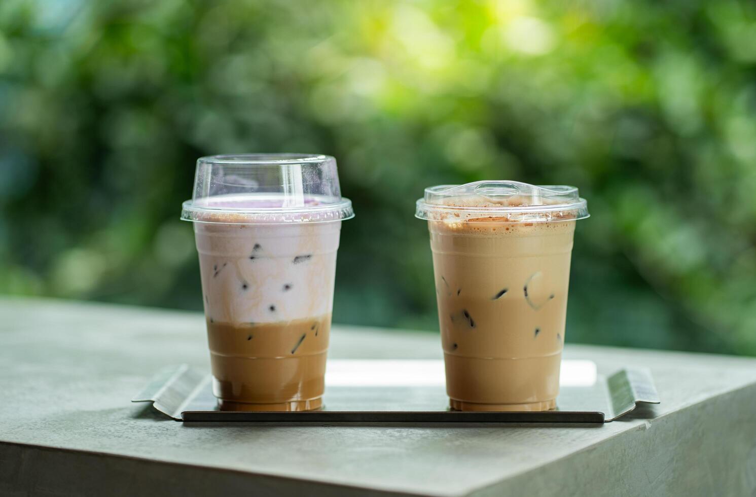Close up glass of ice coffee with taro milk and ice cappucino on raw cement table of a coffee shop summer terrace. photo