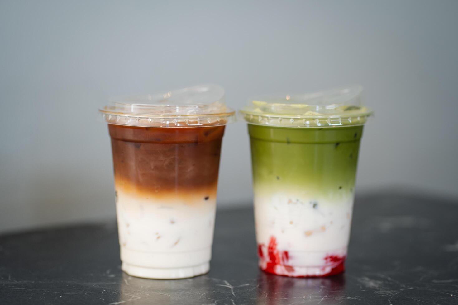 Close up glass of ice matcha green tea with jelly, iced latte on black marble table of a coffee shop summer terrace, menu photography. photo