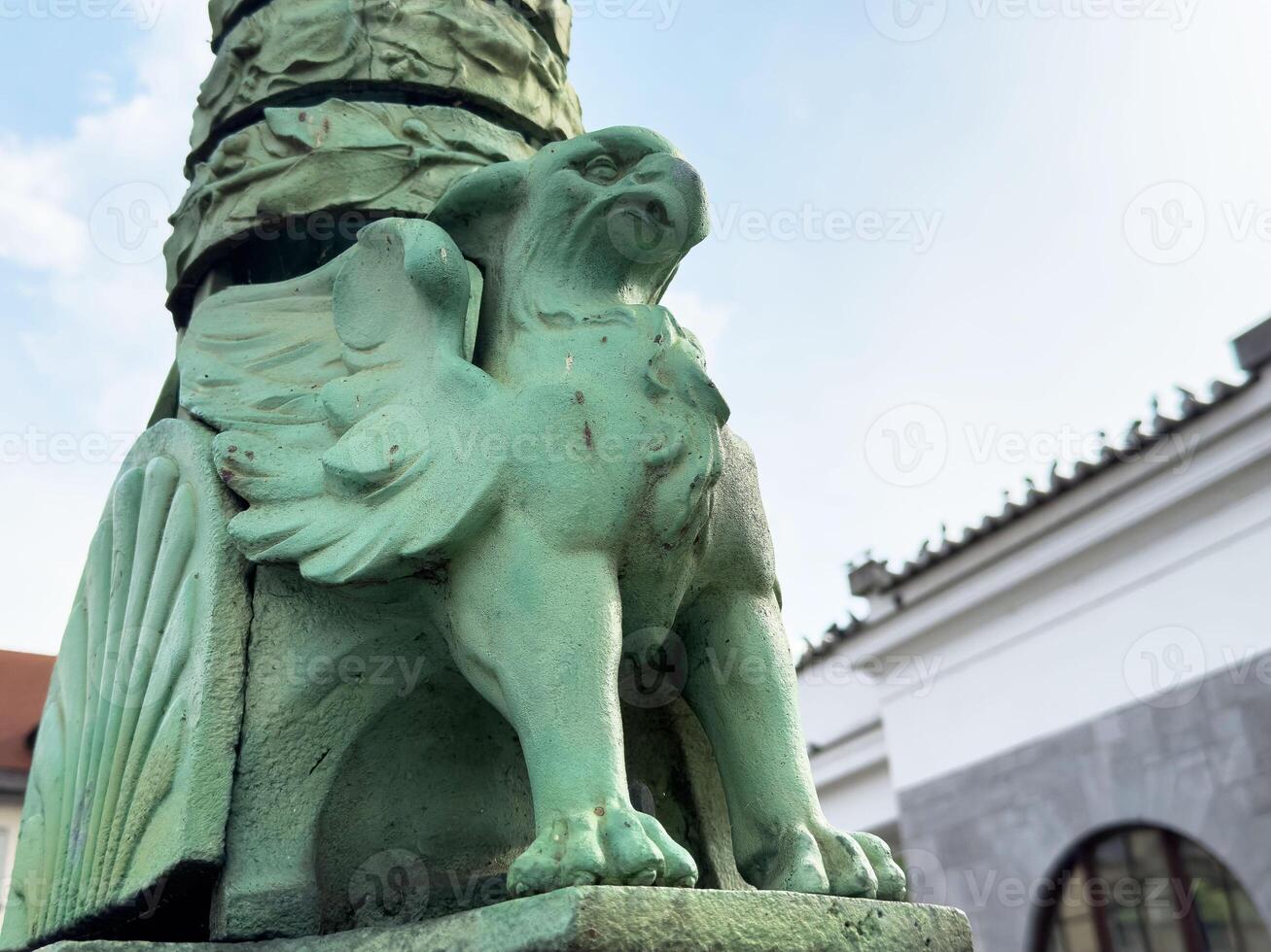 Green mythical creature sculpture with wings on outdoor post photo