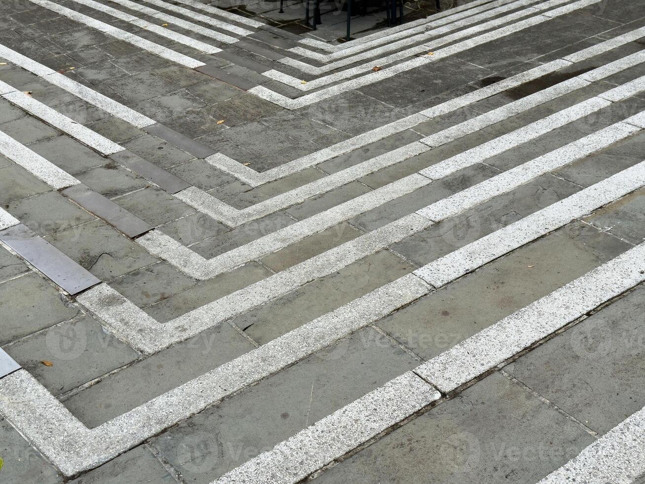 Abstract geometric pattern on gray stone pavement with white lines photo