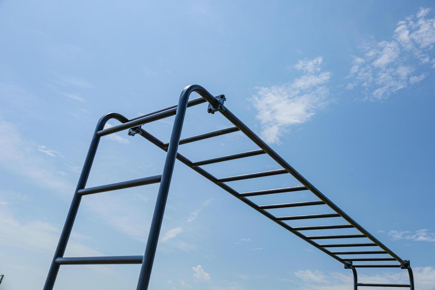 Gymnast engages in strength training on horizontal parallel bars under a clear blue sky, highlighting dedication to fitness and health photo