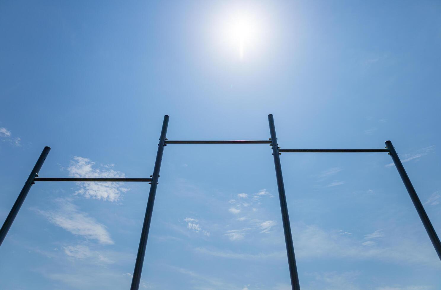 Under a clear blue sky, horizontal gym bars are positioned for athletes to practice strength and gymnastics, promoting healthy living photo