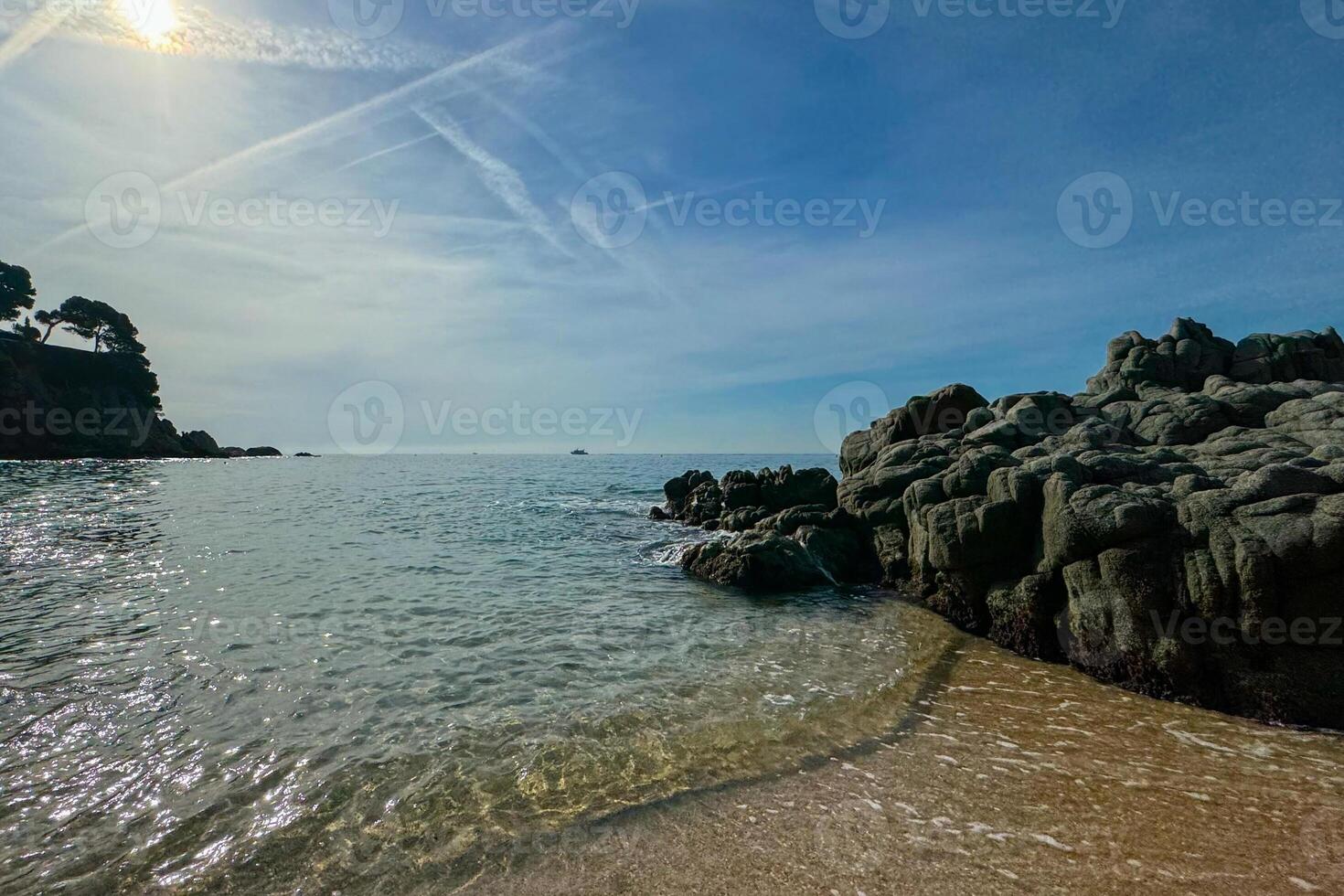 A stunning beach landscape in Lloret de Mar, Spain, with clear blue skies and visible airplane trails. The perfect summer scene with space for text or copy. photo