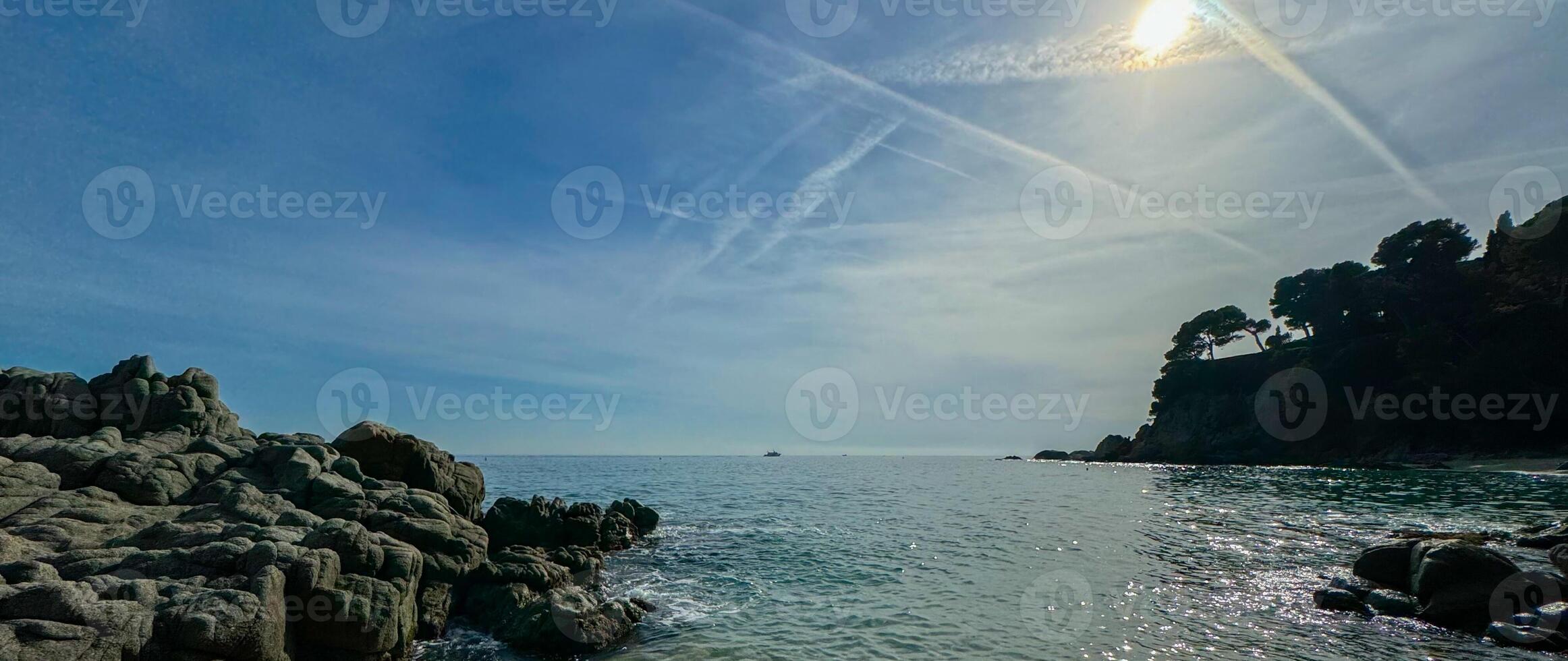 A breathtaking beach landscape in Lloret de Mar, Spain, featuring massive rocks and cliffs along the coastline. The natural beauty of the area is perfect for outdoor and travel banner photo