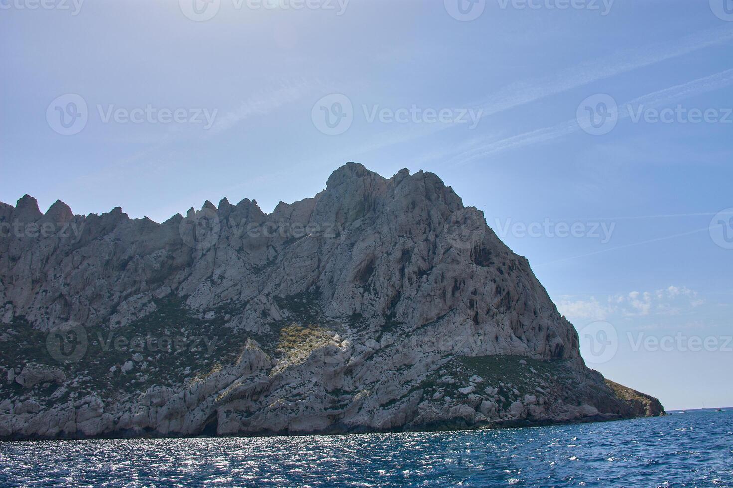 View from a moving boat toward the Calanques of Marseille, highlighting the contrast between the blue sea and the rock formations photo