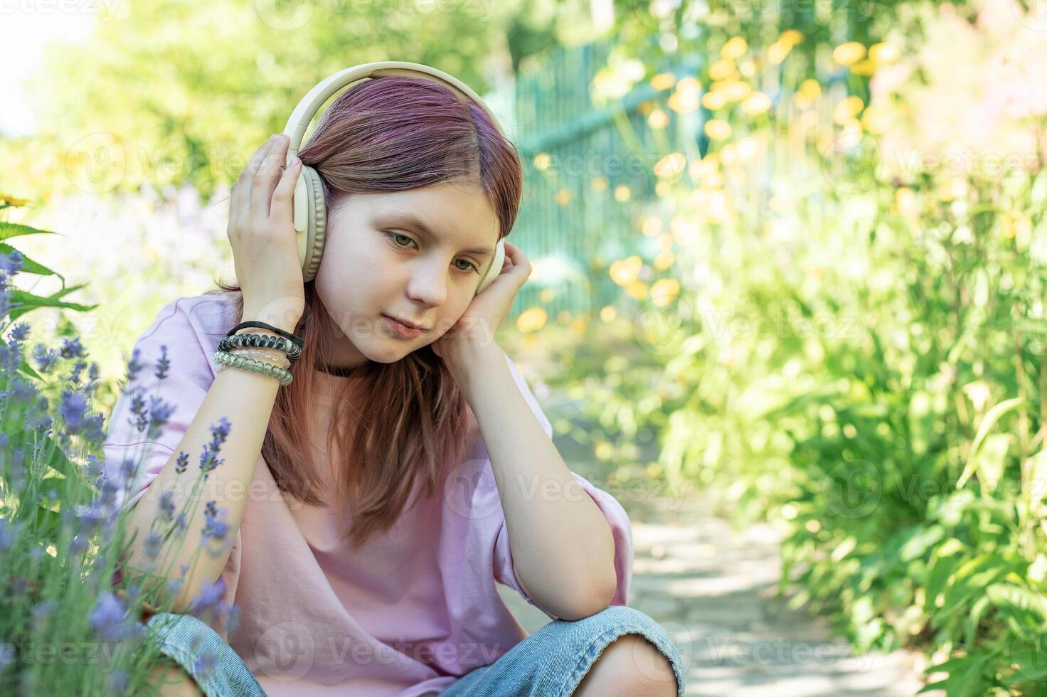 Teenager girl listening music with headphones in garden photo