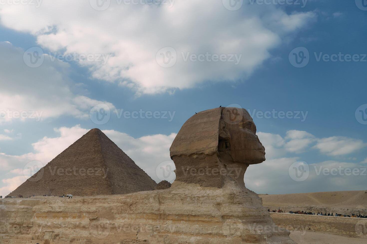 The iconic Great Sphinx and Pyramid stand majestically beneath a dramatically cloudy sky photo