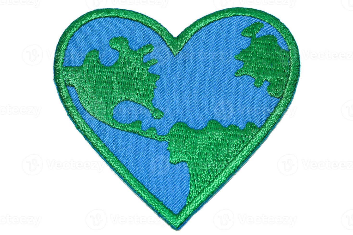 Horizontal photo of heart shaped world embroidery in green and blue thread on white background. Perfect for earth day, eco friendly and global warming themes.